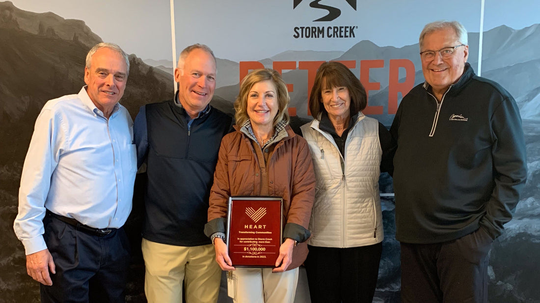 Group of people posing together with a plaque in front of a 'Storm Creek' sign.